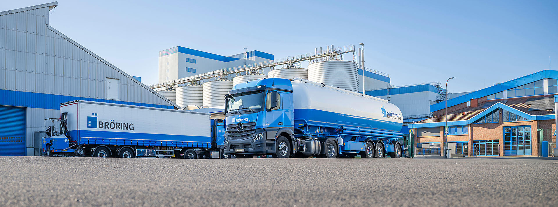 Silo-LkW und Sackwaren-LKW aus der Froschperspektive stehen vor dem Mischfutterwerk in Dinklage, rechts ist der Agrarmarkt zu sehen, links die Düngerhalle