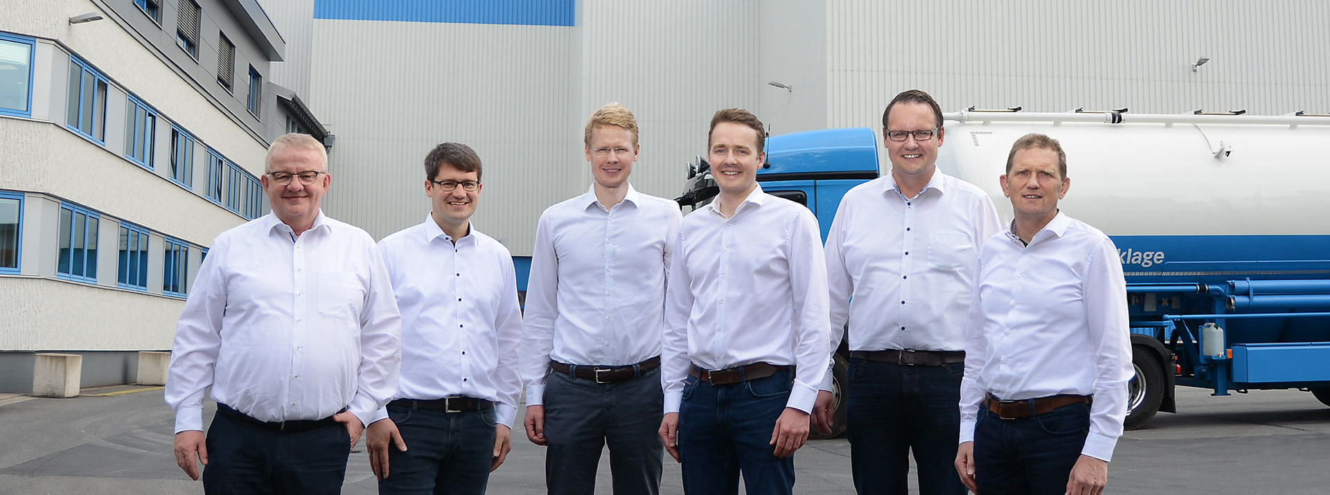 Geschäftsführung der BRÖRING Unternehmensgruppe vor dem Produktionswerk in Dinklage. Im Hintergrund vor dem Produktionswerk ist ein Silo-LKW zu sehen.